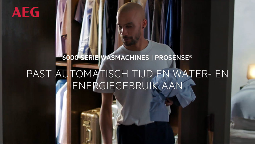 Een man staat voor een open kledingkast met kleding en een koffer. Er is tekst over wasmachines.