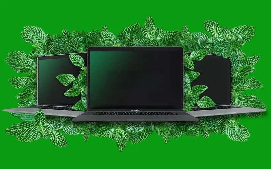 Three MacBook Pro laptops surrounded by green leaves on bright green background, sustainability and nature concept.