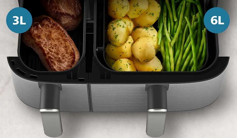 In a Philips air fryer there are steaks in the left 3L drawer and potatoes with green beans in the right 6L drawer.