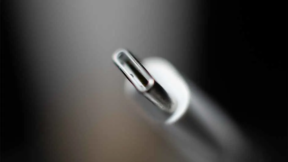 Een close-up van een witte USB-C-connector tegen een vage grijze achtergrond, met de metalen binnenkant van de connector zichtbaar.