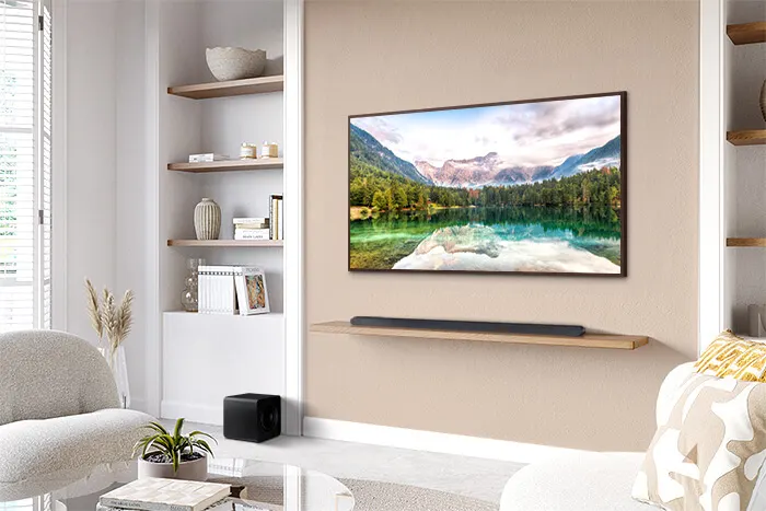Een woonkamer met een tv met een bergzicht, een soundbar op een plank, een witte stoel en een open kast.