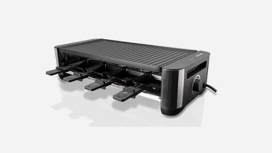 Een zwarte raclette grill met vier pannetjes staat op een witte achtergrond. Het apparaat heeft een geribbeld oppervlak.