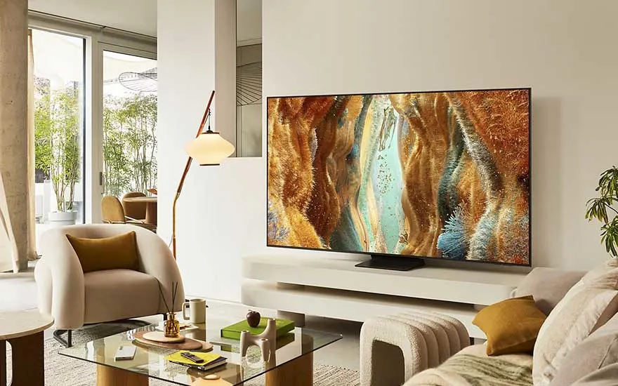 Stylish living room with white furniture and a TV on a low stand, displaying colourful, organic-looking digital artwork.