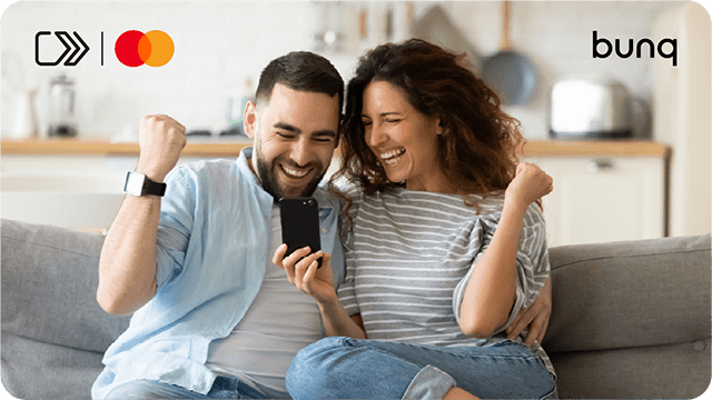 Blij koppel juicht op de bank met telefoon; logo’s van Mastercard en bunq in beeld.