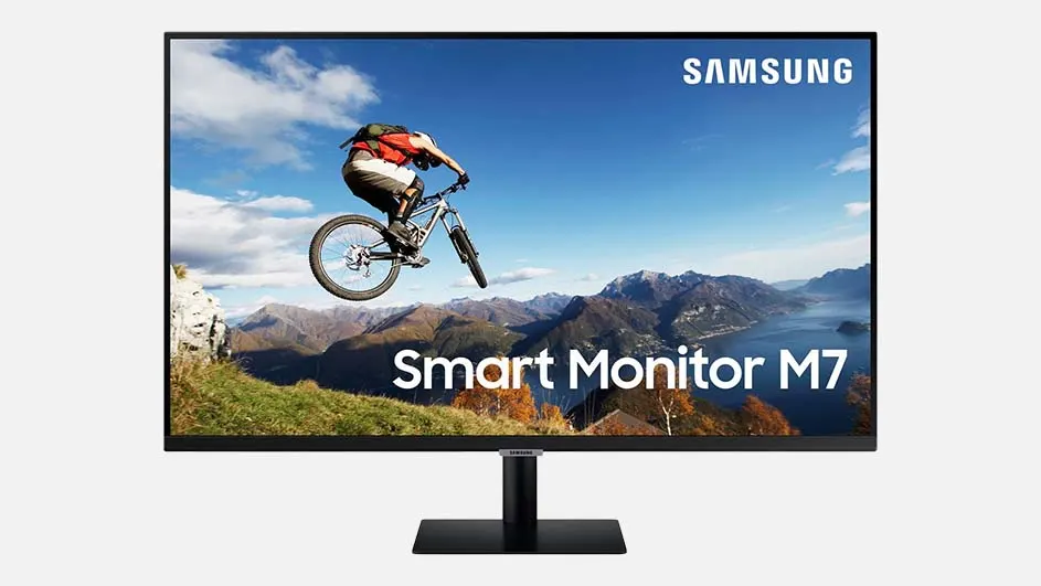 Een zwarte Samsung monitor met een scherm waarop een fietser over bergen springt onder een blauwe lucht.
