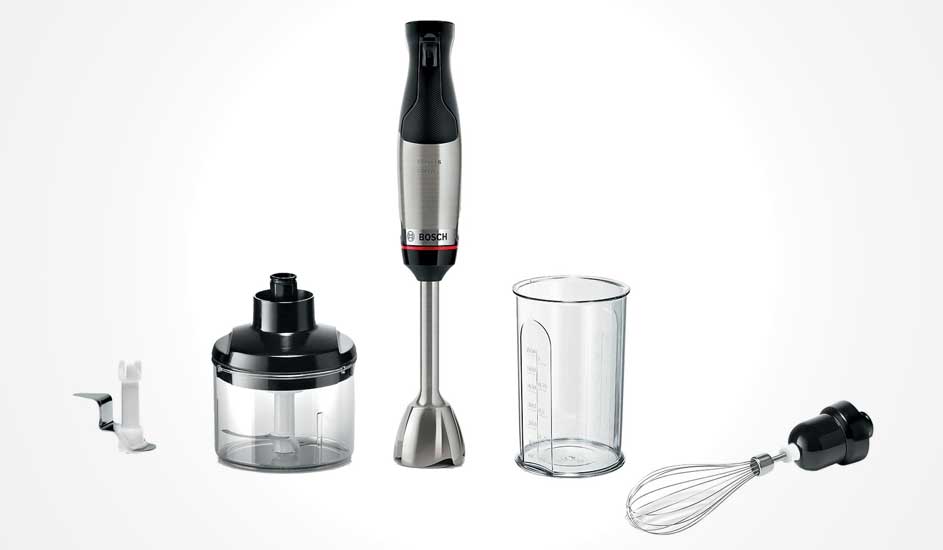 Bosch staafmixer in zwart en zilver met hakmolen, maatbeker, garde en extra mes, alle onderdelen netjes uitgelijnd op witte achtergrond.