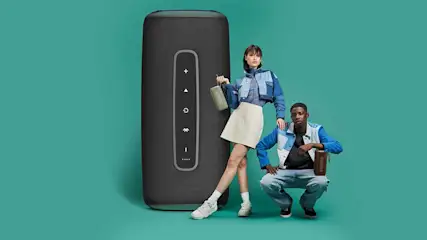 Zwarte luidspreker met knoppen, staande vrouw met kleine luidspreker en gehurkte man op een blauwe achtergrond.