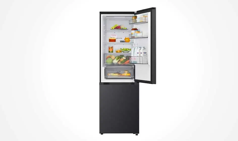 Een zwarte koel-vrieskast staat open, met eten op glazen planken, flessen in de deur en een onderste vrieslade tegen een witte achtergrond.