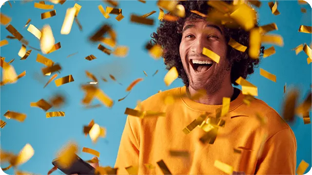 Vrolijke persoon met telefoon tussen gouden confetti op blauwe achtergrond.