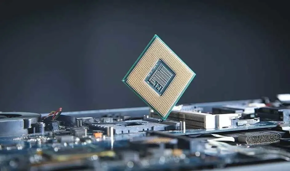 Een processorchip zweeft boven een moederbord; je ziet pinnen, sleuven en metalen onderdelen in een close-up met onscherpe achtergrond.