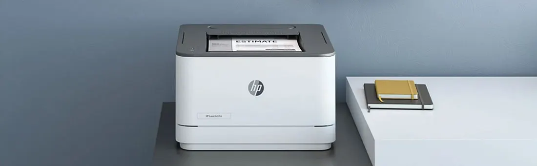 Witte HP-laserprinter op een strak bureau, grijze muur met kunst en plankje; een document wordt net geprint. Merk: HP.