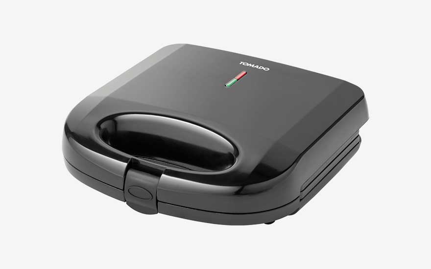 Glanzend zwart Tomado tosti-ijzer met afgeronde vormen, warmtelampjes op het deksel en vergrendelclip aan de voorkant.