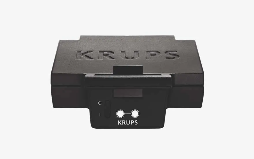 Een compacte zwarte KRUPS-plaat staat frontaal in beeld, met schakelaar en indicatoren op een strakke witte achtergrond.