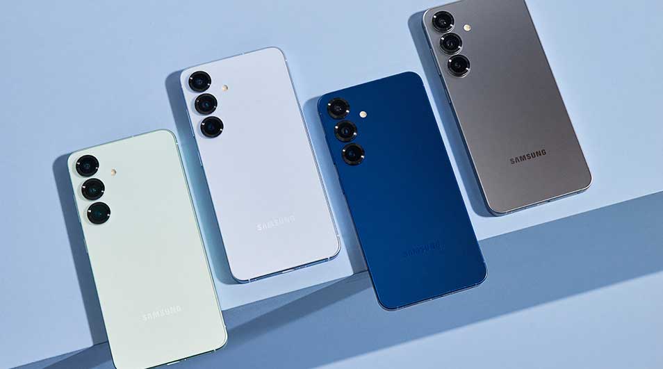 Vier Samsung-smartphones liggen schuin op een lichtblauwe ondergrond en tonen hun achterkant met driedubbele camera’s in diverse kleuren.