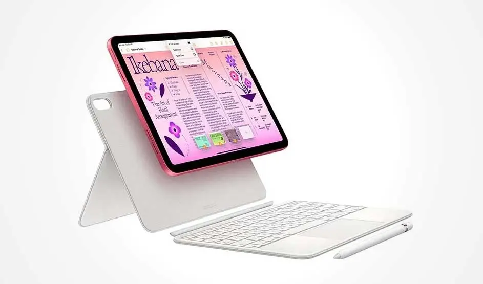 Een roze iPad staat op een witte standaardhoes; op het scherm een lay-out met tekst en paarse bloemen, met een wit toetsenbord en stylus ervoor.
