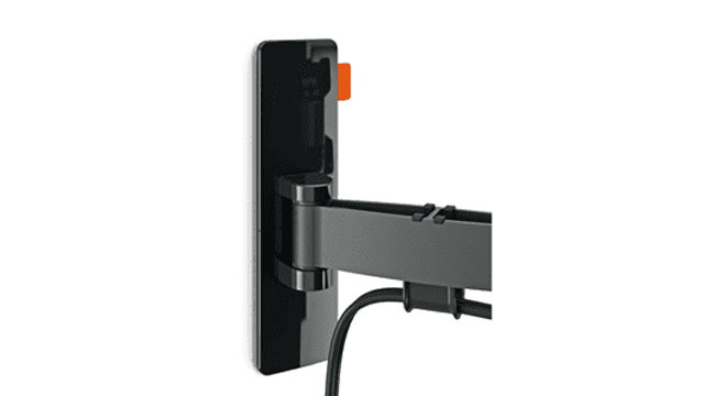 Zwarte tv-muurbeugel met oranje details, bevestigd aan een witte muur met een zwarte kabel die naar beneden hangt.