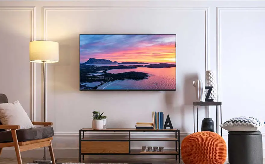In een stijlvolle woonkamer hangt een flatscreen-tv aan de muur, die een kleurrijke zonsondergang boven een eiland laat zien.