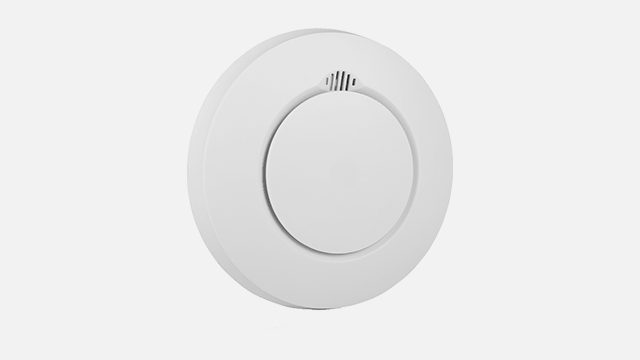 Een ronde, witte rookmelder met een kleinere ronde knop in het midden, tegen een witte achtergrond.