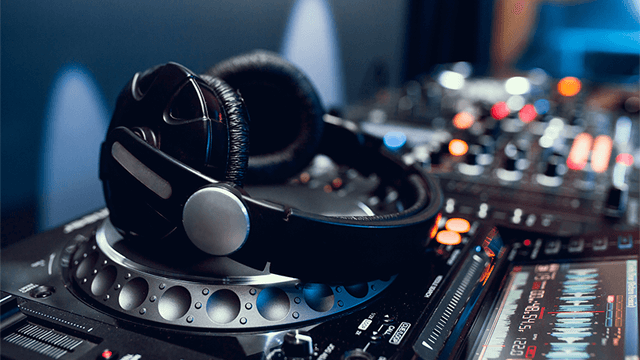 Zwarte hoofdtelefoon op een draaitafel, met een mengpaneel op de achtergrond.