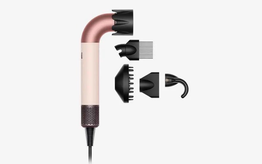 Modern rose gold and white hairdryer shown on its side, surrounded by several black attachments for styling, curls and gentle drying.