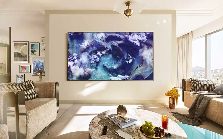 Luxe leefruimte met grote ramen, een stijlvolle bank en een tv aan de muur met een kunstzinnige afbeelding van blauwe wolken.