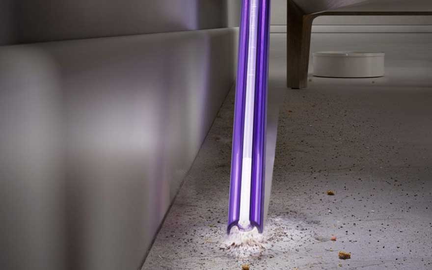 Een persoon stofzuigt een houten vloer met een klassieke sledestofzuiger, ideaal voor dagelijks schoonmaken.