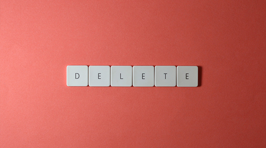 Zes witte toetsenbordtoetsen met de letters 'DELETE' liggen op een effen rode achtergrond.