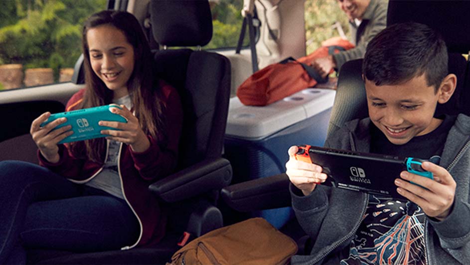 Twee kinderen zitten op de achterbank van een auto en spelen spelletjes op een Nintendo Switch.