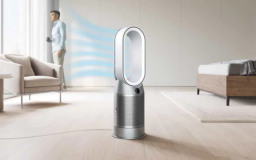 Moderne torenluchtreiniger in een minimalistische slaapkamer, blaast zachte blauwe luchtstromen uit terwijl een man bij het raam staat.