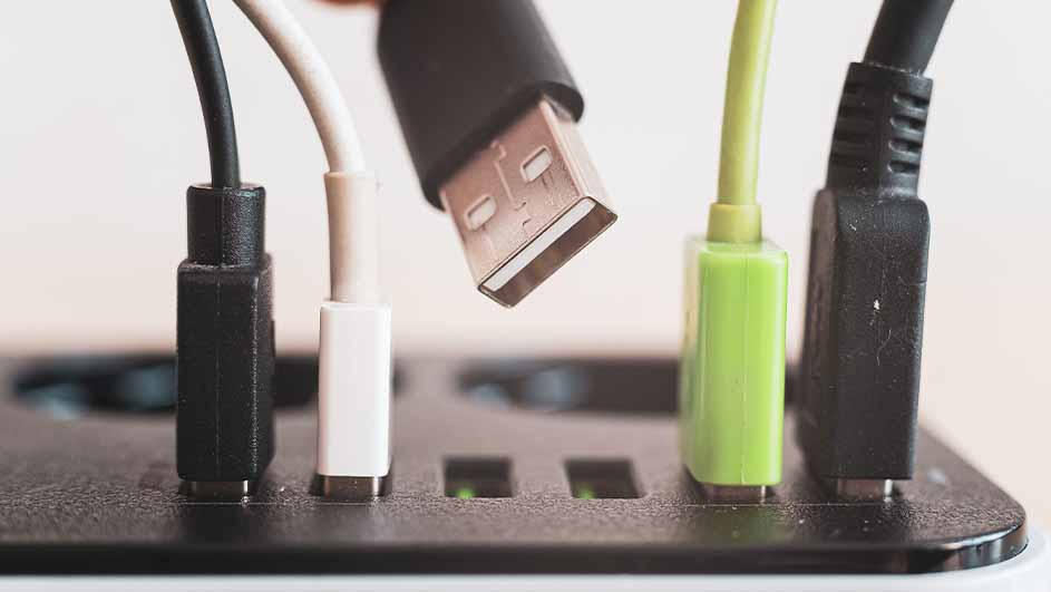 Diverse USB-kabels, zwart, wit en groen, zijn aangesloten op een zwart USB-station tegen een witte achtergrond.