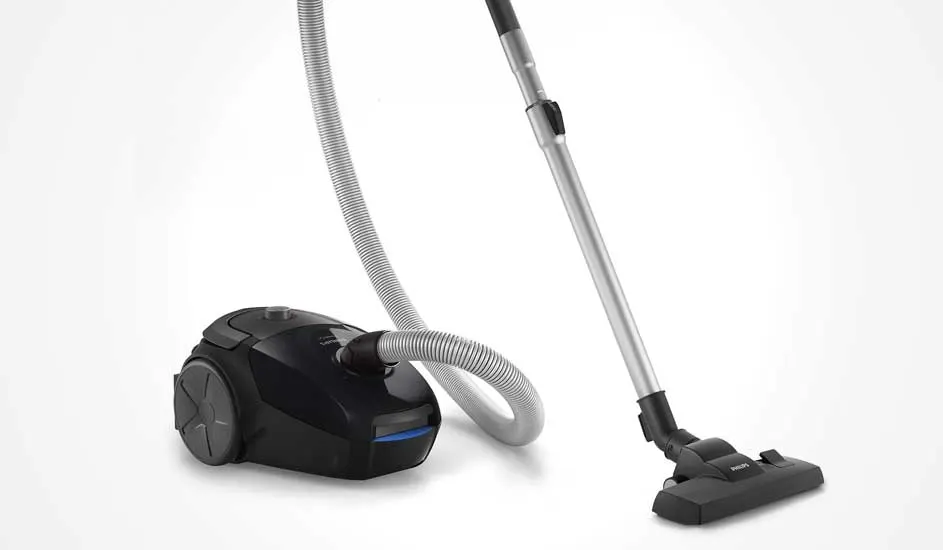 A compact black cylinder vacuum with silver tube and flexible hose is shown alone against a clean, bright white background.