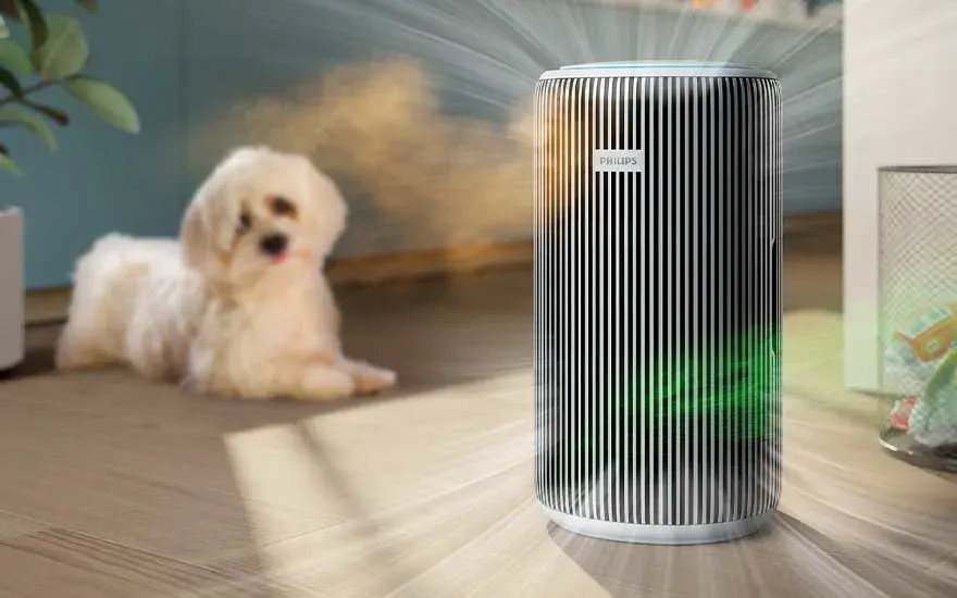 Een verticale Philips-luchtreiniger straalt frisse lucht door de kamer, terwijl op de achtergrond een kleine witte hond ontspannen op de vloer ligt.