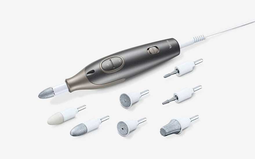 Een elektrische manicure- en pedicureset met meerdere opzetstukken ligt overzichtelijk op een witte achtergrond.