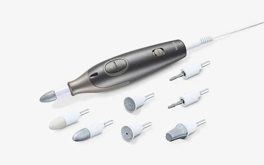 Een elektrische manicure- en pedicureset met meerdere opzetstukken ligt overzichtelijk op een witte achtergrond.