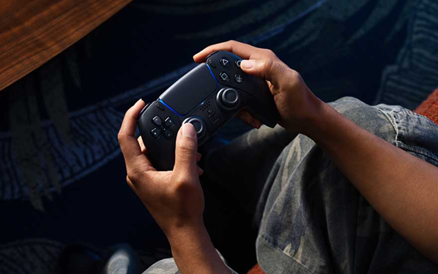Someone grips a black game controller with both hands, thumbs poised on the sticks, fully focused and ready to react in‑game.