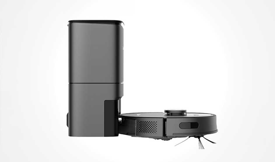 Een zwarte robotstofzuiger staat zijwaarts naast een hoog basisstation; je ziet ventilatieroosters, zijborstels en de verhoogde sensor bovenop.
