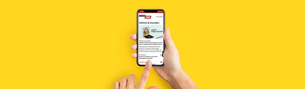 Hand houdt een zwarte smartphone met een nieuwsartikel op een gele achtergrond. Een vinger wijst naar het scherm.