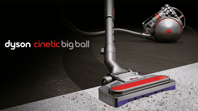 Een grijze Dyson stofzuiger met rode en paarse details staat op een oppervlak, tegen een zwarte achtergrond.