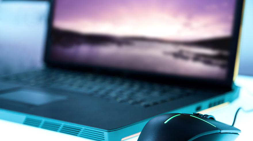 Laptop met paars scherm en een zwarte muis met groene accenten op een witte ondergrond.