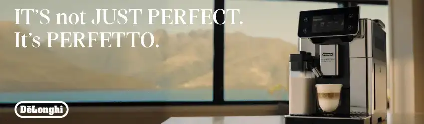 De’Longhi advertentie met een zilveren volautomatische espressomachine die een cappuccino zet in een moderne keuken met berguitzicht en de slogan: “It’s not just perfect. It’s perfetto.”
