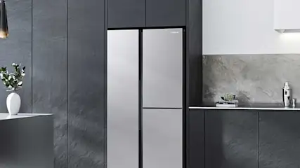 Moderne donkergrijze keuken met grote side-by-side koelkast, marmeren werkblad, eiland en minimalistische zwarte kasten design.