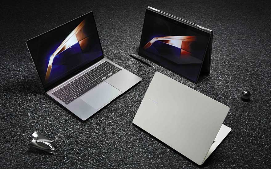 Three slim laptops sit on a dark textured floor; one open, one in tent mode and one closed, each showing vivid modern display imagery.