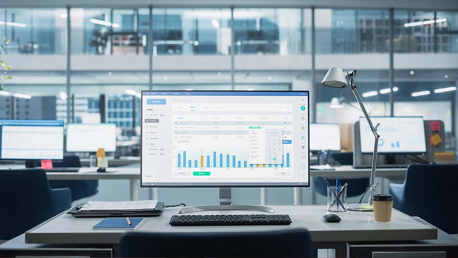 Open kantoor met bureau, computer met grafiek, toetsenbord, lamp, koffiebeker en kantoorbenodigdheden.