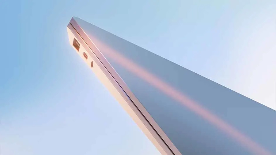 Een dunne, zilverkleurige laptop wordt schuin van onderen gefotografeerd tegen een blauwe lucht. Merknaam: Microsoft Surface.