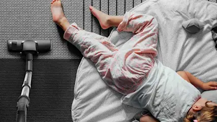 Een slapend kind naast een stofzuiger benadrukt de stilte en zachtheid van het toestel, geschikt voor gezinnen met kinderen.