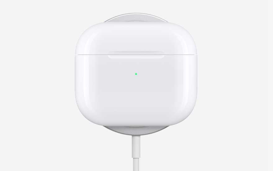 A glossy white AirPods charging case stands upright, connected by a cable, with a tiny green status light glowing on the front.