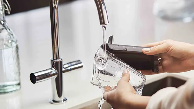 Een kraan vult een doorzichtige kan met water. De kan wordt vastgehouden boven een gootsteen en ernaast staat een glazen fles.