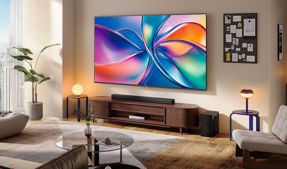 A luxury living room with a large wall-mounted television displays colourful abstract artwork in purple, blue, orange and green. Wooden furniture, warm lighting, potted plant, armchairs. Modern, elegant design with city views.
