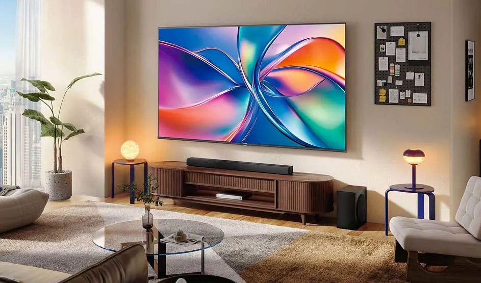 Een luxe woonkamer met grote wandmontage-tv toont kleurrijke abstracte kunstwerken in paars, blauw, oranje en groen. Houten meubels, warm licht, plant, fauteuils. Moderne, elegante design met stadsuitzicht.