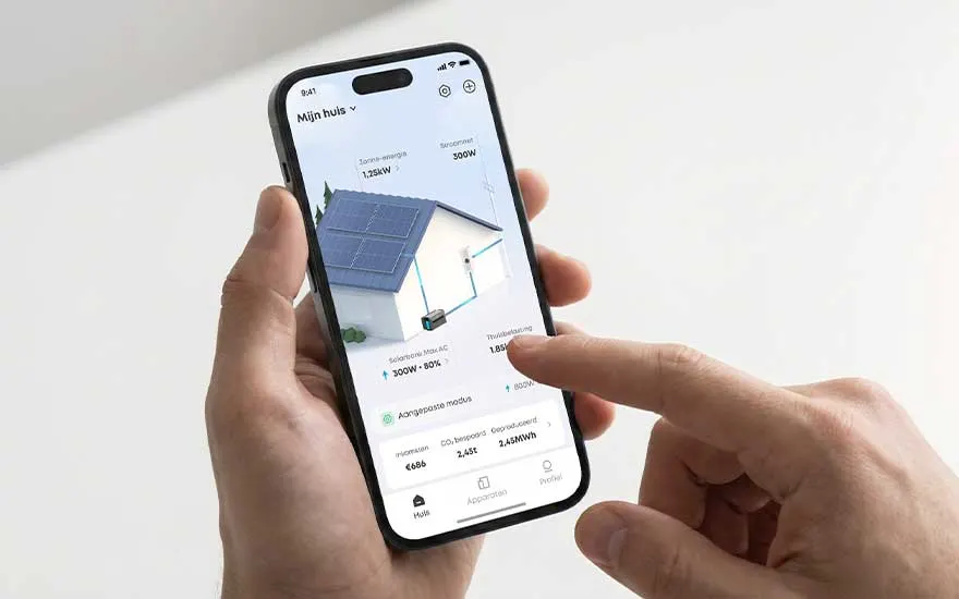 Handen houden een smartphone vast met een app die zonne-energiebeheer toont, inclusief een 3D-huis met zonnepanelen.